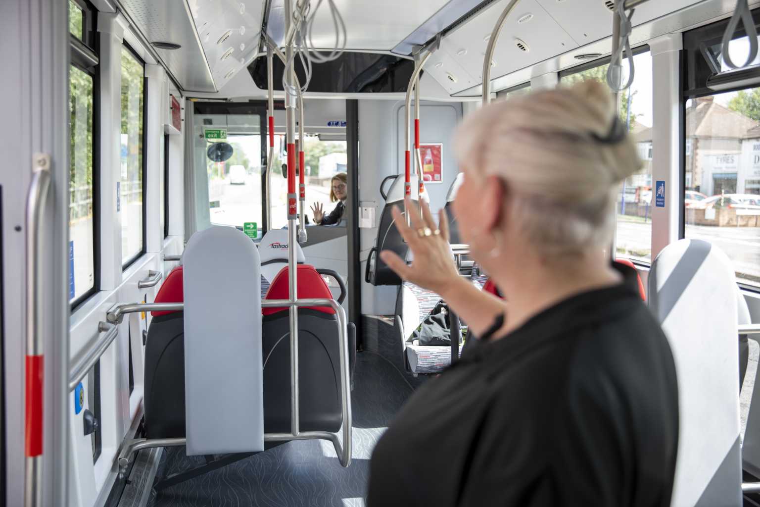 Woman waving at bus driver as she gets off